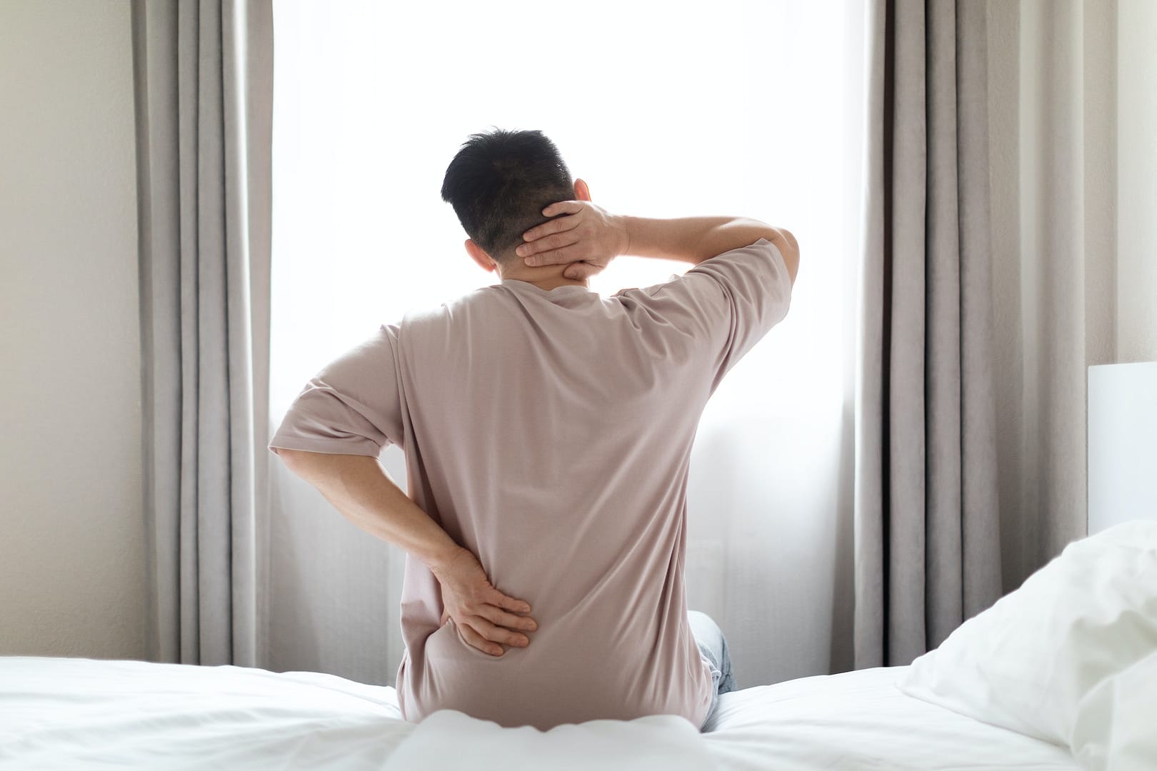 Tired man suffering from back pain from a bad mattress Back Pain care from the Back Pain Project Stamford Darien Norwalk and New Canaan 203-656-3638
